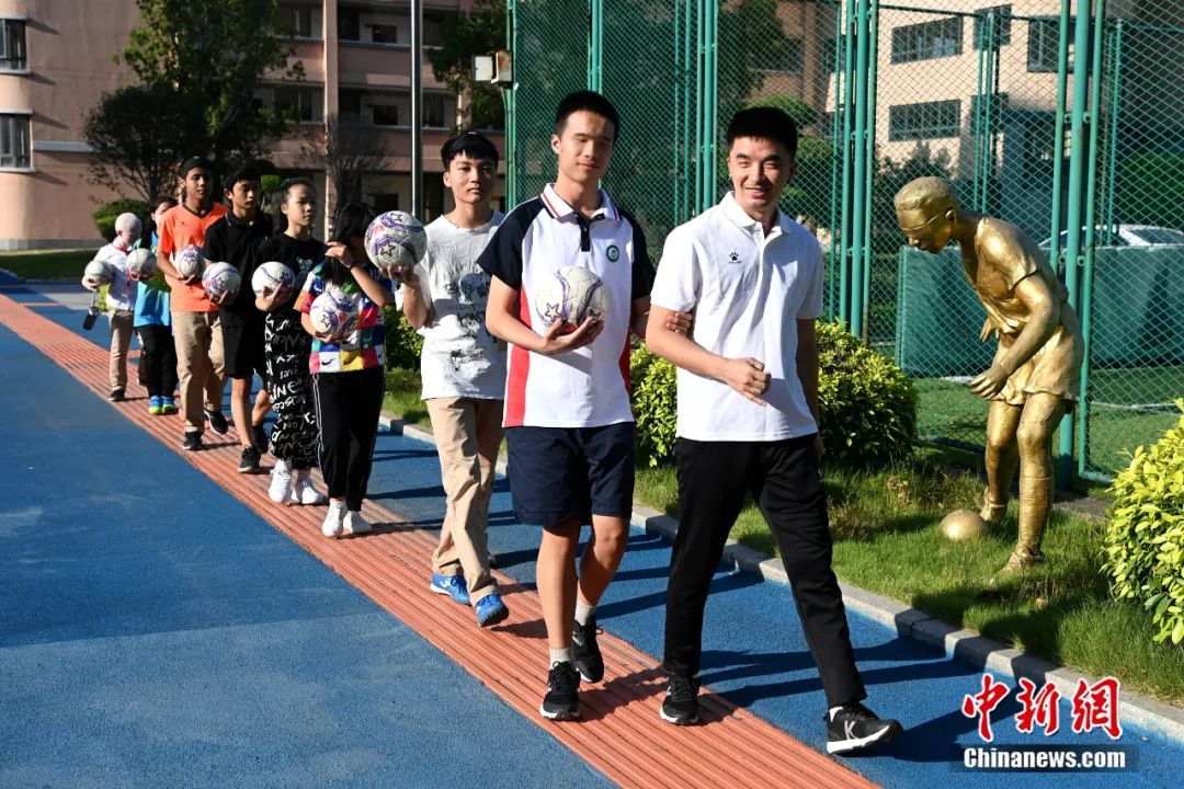 9月8日，王亚锋带着福州盲校里的学生到体育场训练，右边的雕塑是盲校以他为原型设立的。王东明 摄