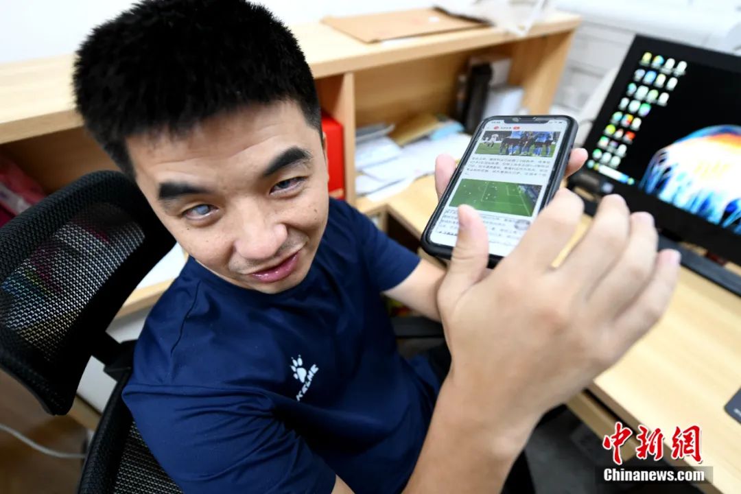 王亚锋使用手机收听世界各地的足球新闻，通过手机上的盲人专用软件，他可以看新闻、聊微信、发朋友圈、网购等，和平常人几乎一样。王东明 摄