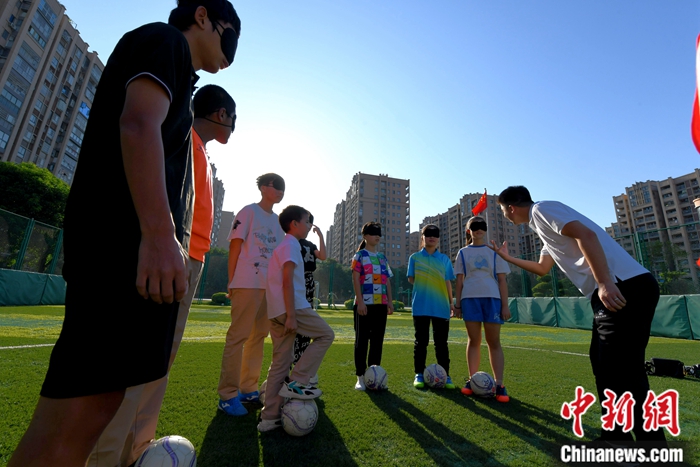 图为9月8日，王亚锋（右一）在盲校足球场指导盲人学生踢球。中新社记者 王东明 摄