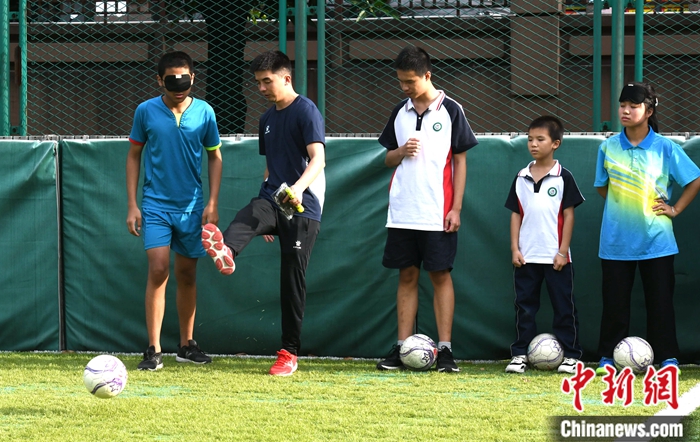 图为9月7日，王亚锋（左二）在盲校足球场指导盲人学生踢球。中新社记者 王东明 摄
